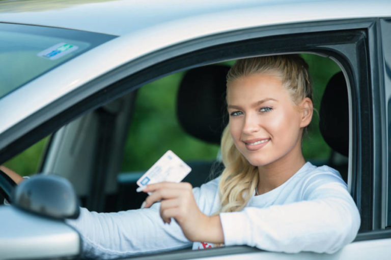 Jonge lachende vrouw laat haar rijbewijs zien